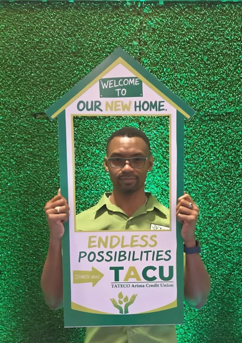 Member posing with TACU photo frame prop reading Welcome to Our New Home at the 72nd AGM