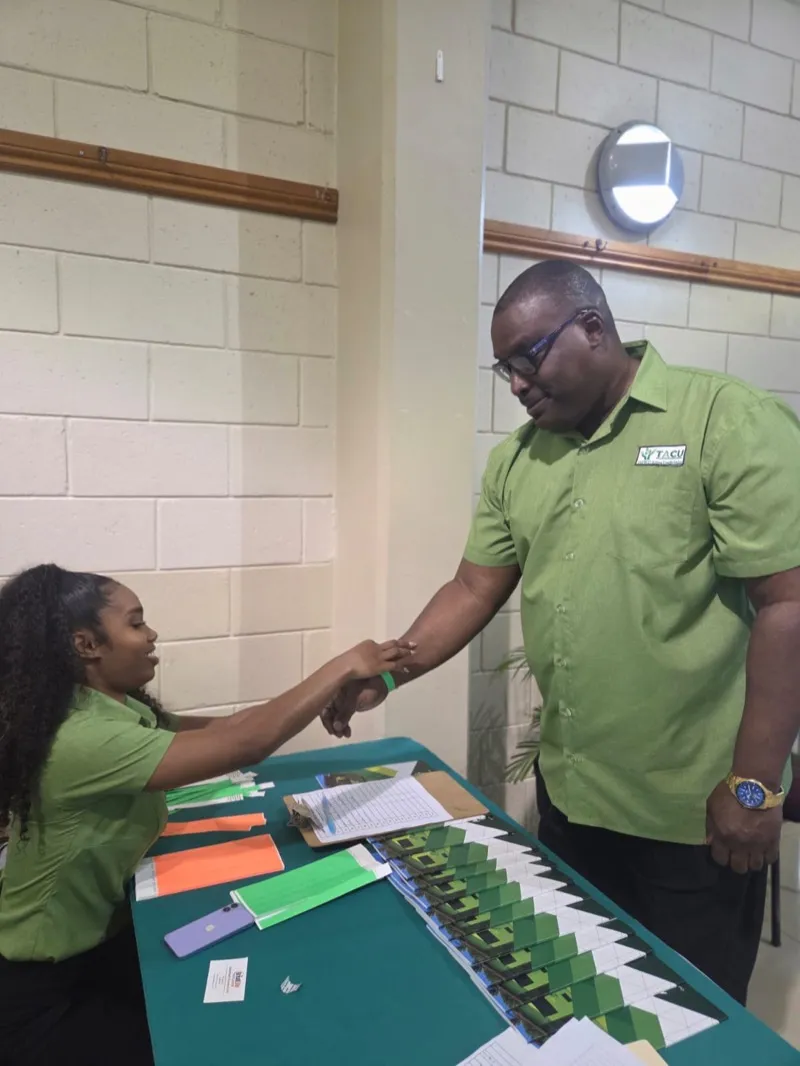 Two TACU staff members in green shirts at the registration table